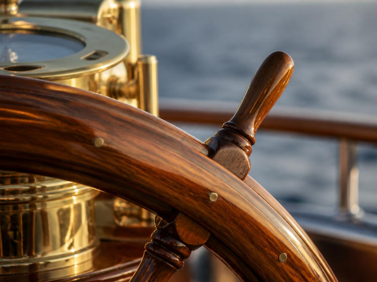 Varnished teak helm wheel and brass binnacle on a luxury yacht